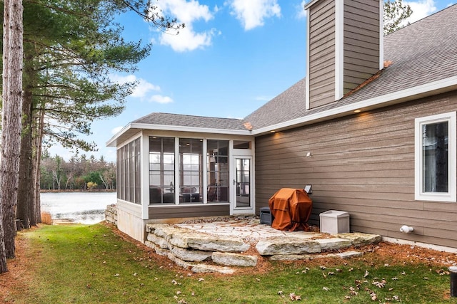 back of house with a water view, a lawn, and a sunroom