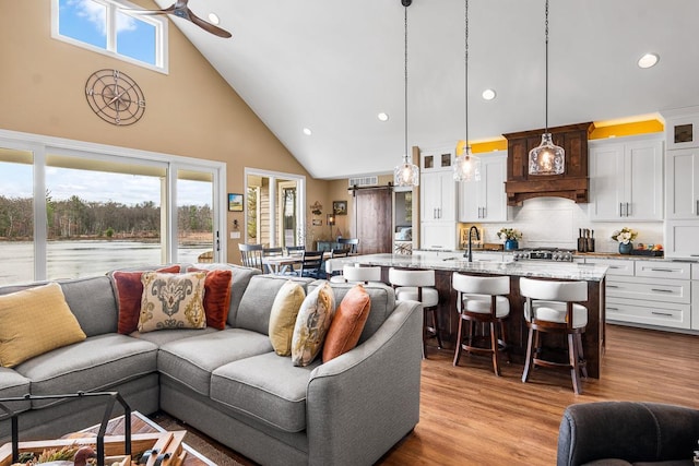 living room featuring light hardwood / wood-style flooring, high vaulted ceiling, a wealth of natural light, and ceiling fan