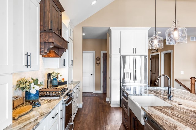 kitchen featuring light stone counters, decorative light fixtures, lofted ceiling, decorative backsplash, and appliances with stainless steel finishes