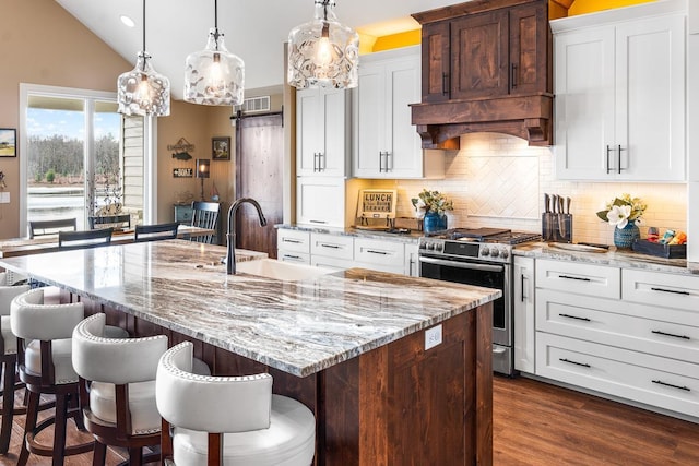 kitchen with stainless steel range, a kitchen bar, a center island with sink, and sink