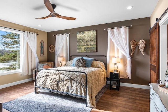 bedroom with hardwood / wood-style floors, ceiling fan, and a barn door