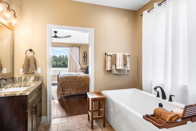 bathroom featuring ceiling fan, hardwood / wood-style floors, vanity, and a bath