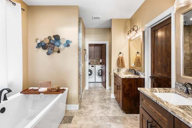 bathroom featuring vanity, washing machine and clothes dryer, and a washtub