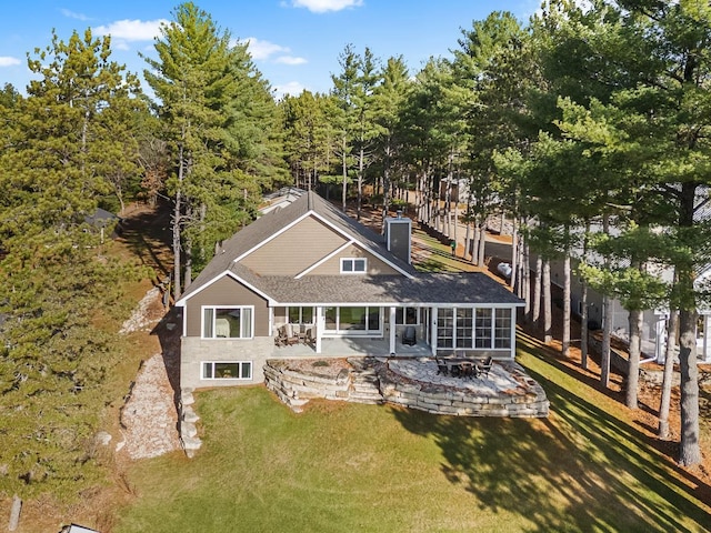 back of property with a lawn, a patio area, and a sunroom