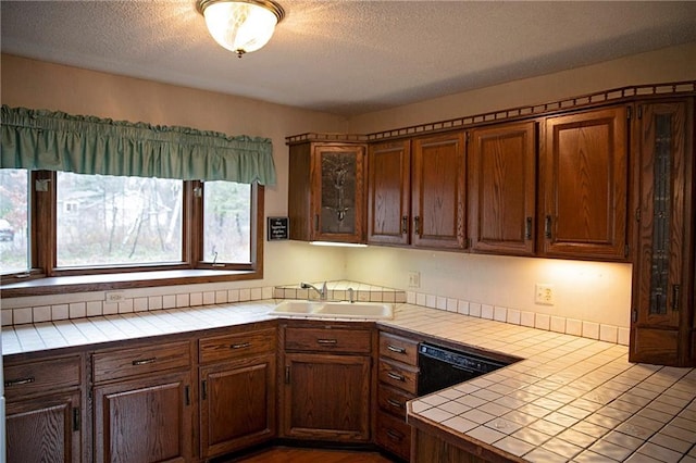 kitchen with dishwasher, tile counters, a textured ceiling, and sink