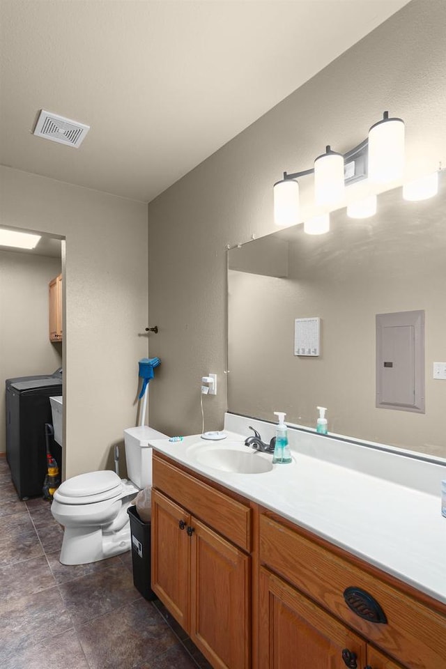 bathroom with washer and clothes dryer, vanity, toilet, and electric panel