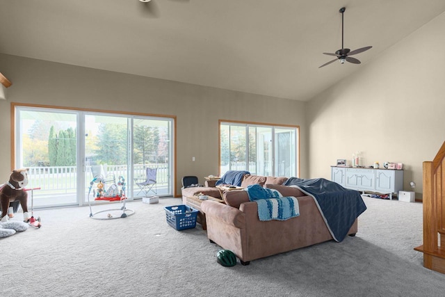 carpeted living room with ceiling fan and high vaulted ceiling