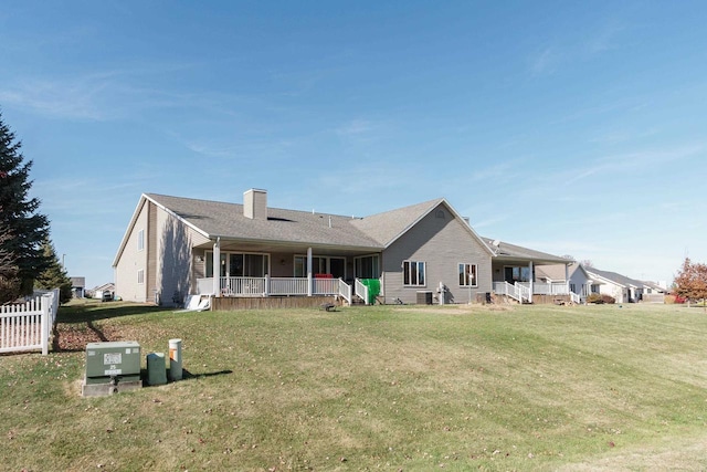 rear view of property featuring a porch and a lawn