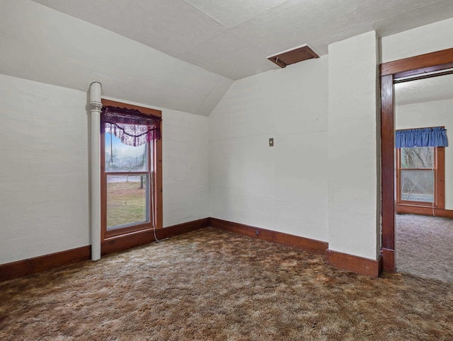 bonus room with vaulted ceiling and dark colored carpet