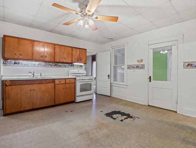 kitchen featuring ceiling fan, sink, tasteful backsplash, a paneled ceiling, and white range with gas cooktop