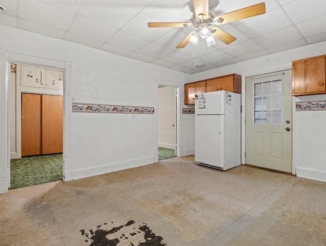 kitchen with a drop ceiling, white refrigerator, and ceiling fan