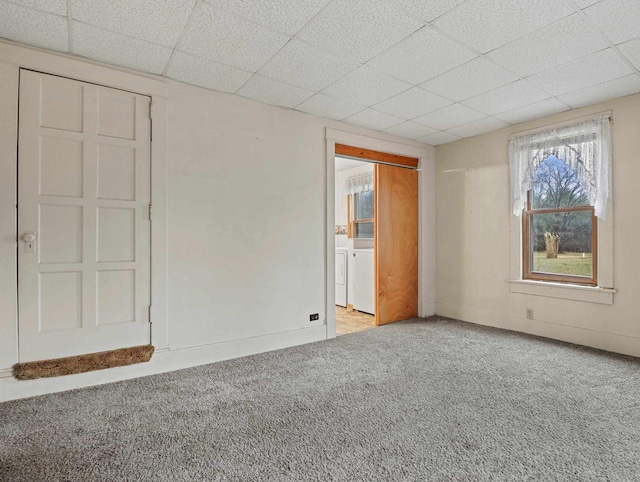 unfurnished bedroom featuring a paneled ceiling, washing machine and dryer, light carpet, and a closet