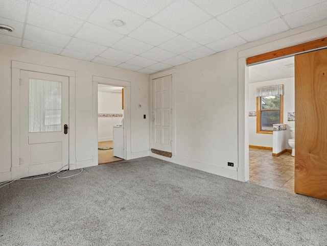 unfurnished bedroom featuring ensuite bathroom, a drop ceiling, and light colored carpet