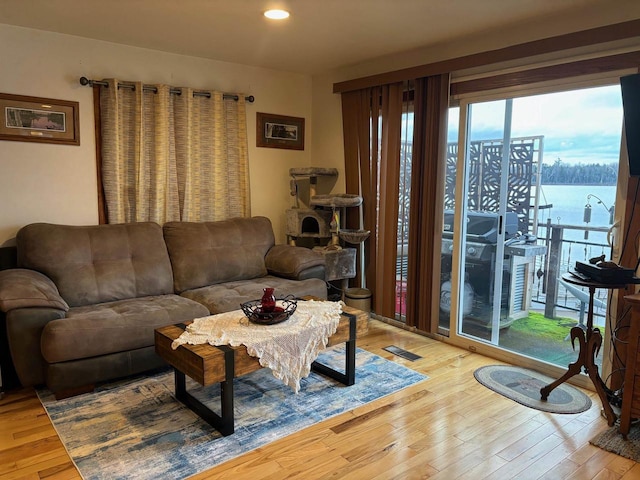 living area featuring a water view, visible vents, wood finished floors, and recessed lighting