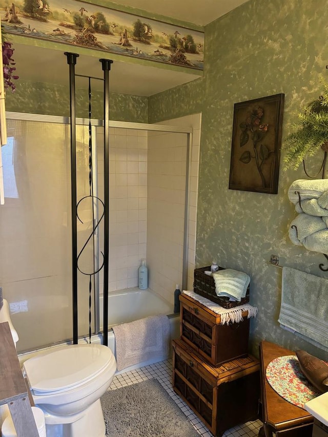 full bath featuring washtub / shower combination, tile patterned flooring, toilet, and wallpapered walls