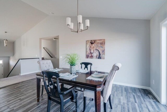 dining room featuring hardwood / wood-style floors, vaulted ceiling, and an inviting chandelier