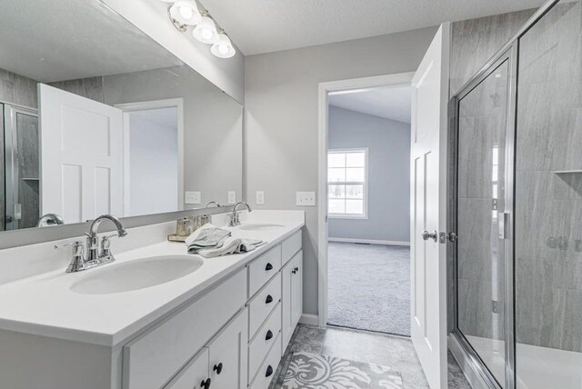 bathroom featuring vaulted ceiling, a textured ceiling, walk in shower, and vanity