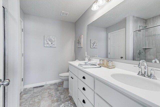 bathroom with a textured ceiling, an enclosed shower, vanity, and toilet