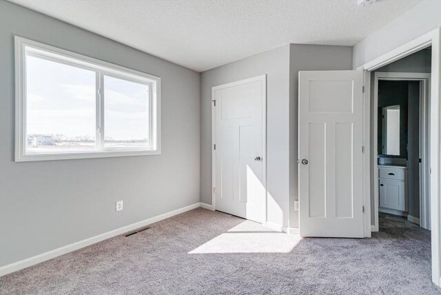 unfurnished bedroom featuring light colored carpet and a textured ceiling