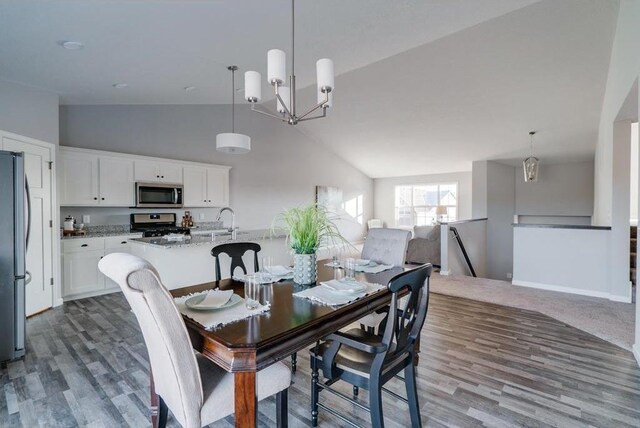 dining room with dark wood-type flooring, sink, high vaulted ceiling, and a notable chandelier