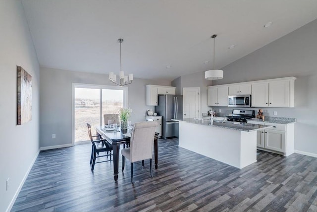 kitchen featuring white cabinetry, an island with sink, stainless steel appliances, light stone countertops, and pendant lighting