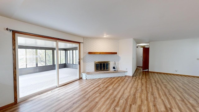 unfurnished living room featuring light wood-type flooring and a brick fireplace