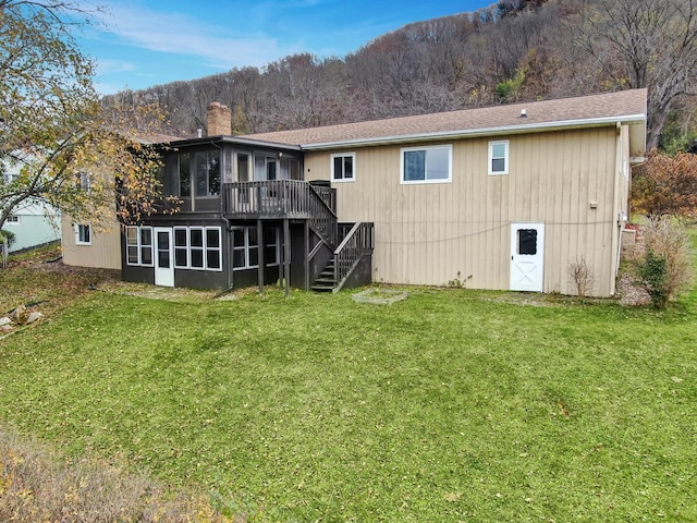 rear view of property featuring a yard, a wooden deck, and a sunroom