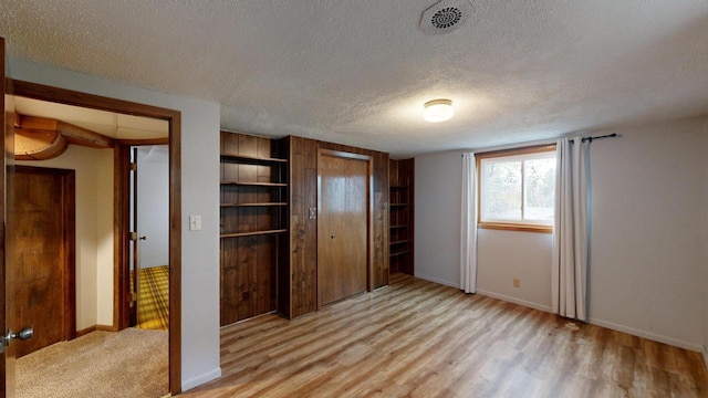 unfurnished bedroom featuring a closet, light hardwood / wood-style flooring, and a textured ceiling