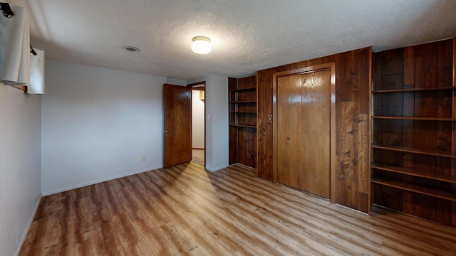 unfurnished bedroom with a closet, a textured ceiling, and light hardwood / wood-style flooring