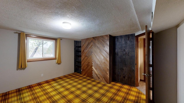 empty room featuring a textured ceiling and wooden walls