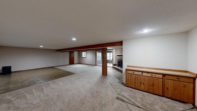 basement with a fireplace, a textured ceiling, and light colored carpet