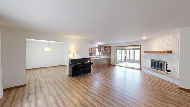 unfurnished living room featuring light hardwood / wood-style floors and a brick fireplace