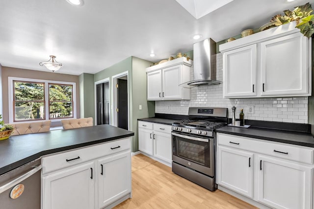 kitchen with white cabinetry, wall chimney range hood, light hardwood / wood-style flooring, backsplash, and appliances with stainless steel finishes