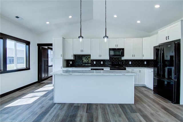 kitchen with white cabinetry, a center island, decorative light fixtures, vaulted ceiling, and black appliances