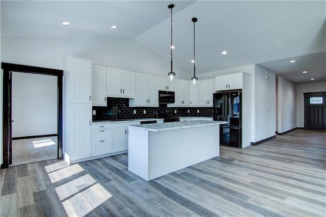 kitchen featuring black appliances, a center island, white cabinets, and light hardwood / wood-style floors