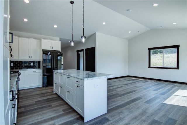 kitchen with black fridge, vaulted ceiling, white cabinets, a kitchen island, and hanging light fixtures