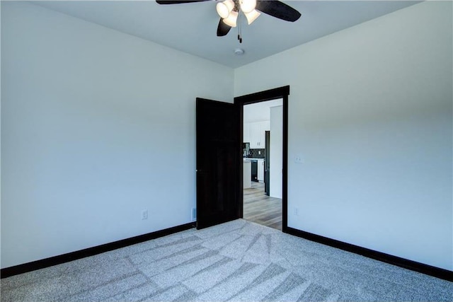 spare room with ceiling fan and light carpet