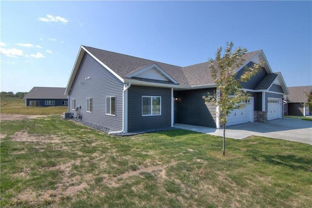 view of front of home with central AC unit, a front yard, and a garage