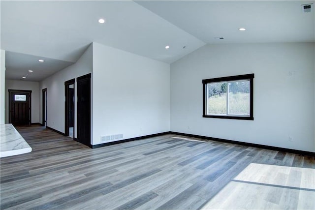 empty room featuring hardwood / wood-style flooring and vaulted ceiling