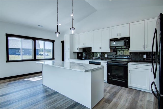 kitchen featuring a center island, lofted ceiling, black appliances, decorative light fixtures, and white cabinetry