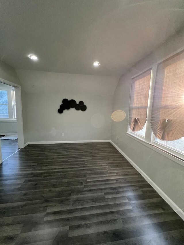 spare room featuring dark wood-type flooring and vaulted ceiling