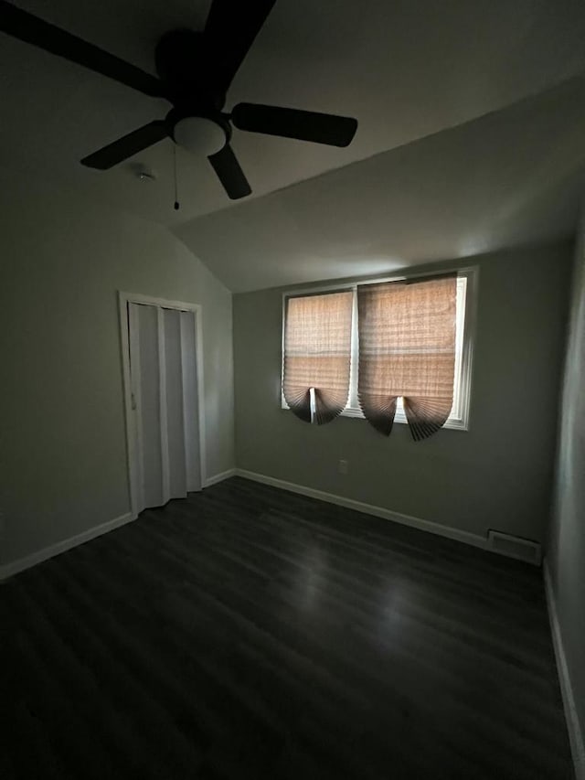 empty room with vaulted ceiling, ceiling fan, and dark wood-type flooring