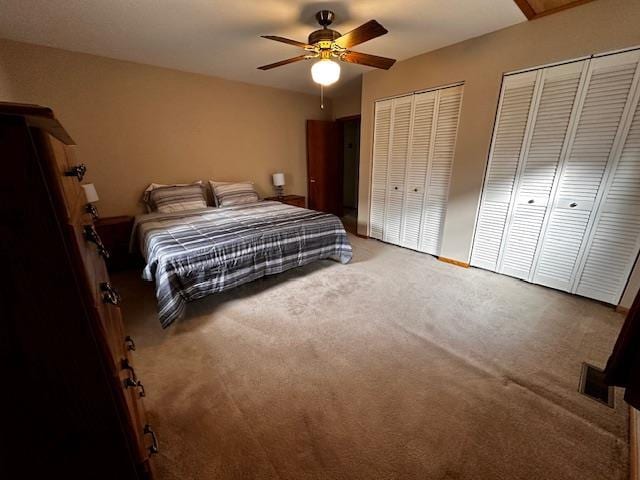 carpeted bedroom featuring ceiling fan and multiple closets