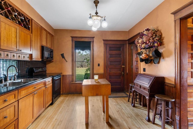 kitchen with sink, backsplash, a chandelier, black appliances, and light wood-type flooring