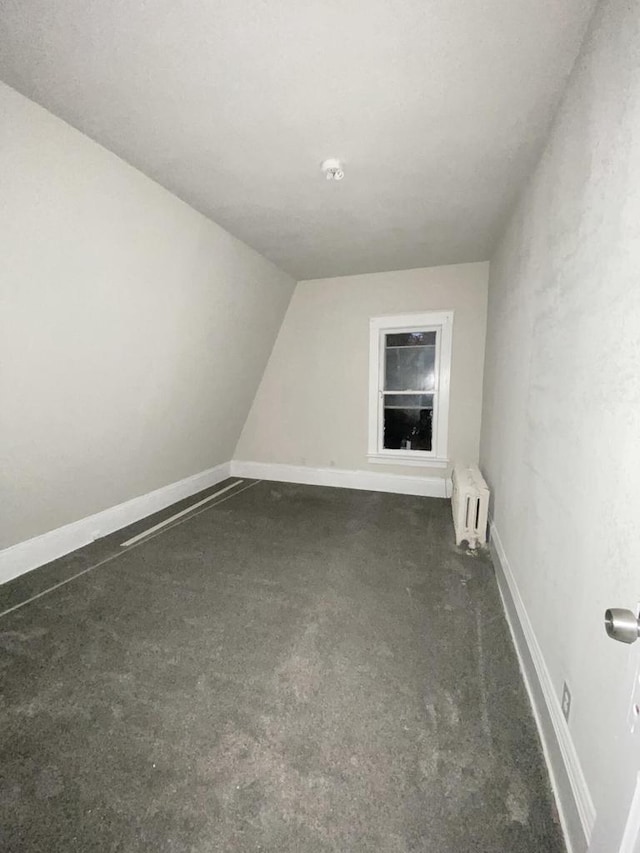 bonus room with radiator, dark colored carpet, and baseboards