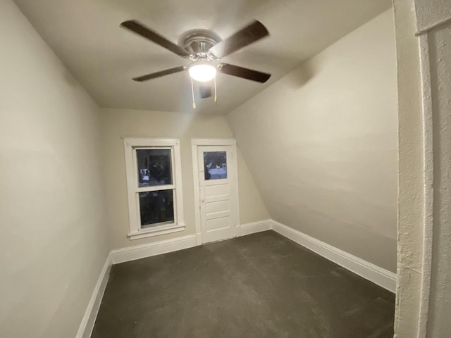 bonus room featuring dark carpet, a ceiling fan, and baseboards