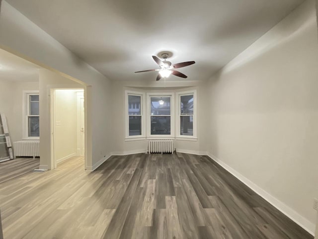 spare room featuring radiator heating unit, a ceiling fan, and wood finished floors