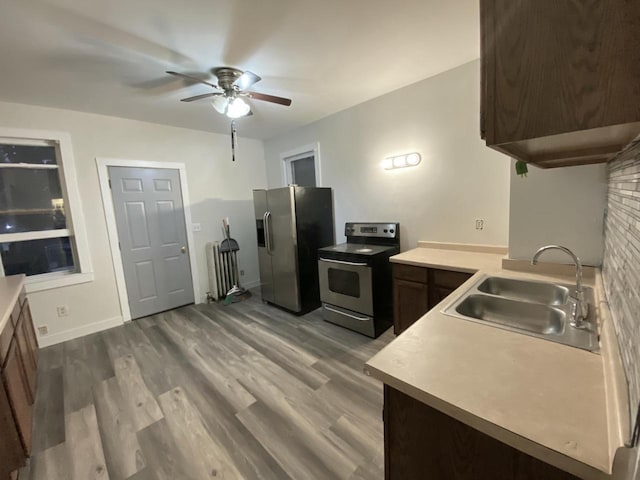 kitchen featuring stainless steel appliances, a sink, a ceiling fan, dark wood-style floors, and light countertops
