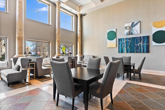 dining space featuring decorative columns, plenty of natural light, and a towering ceiling