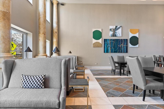 living room featuring tile patterned floors, ornate columns, and a high ceiling